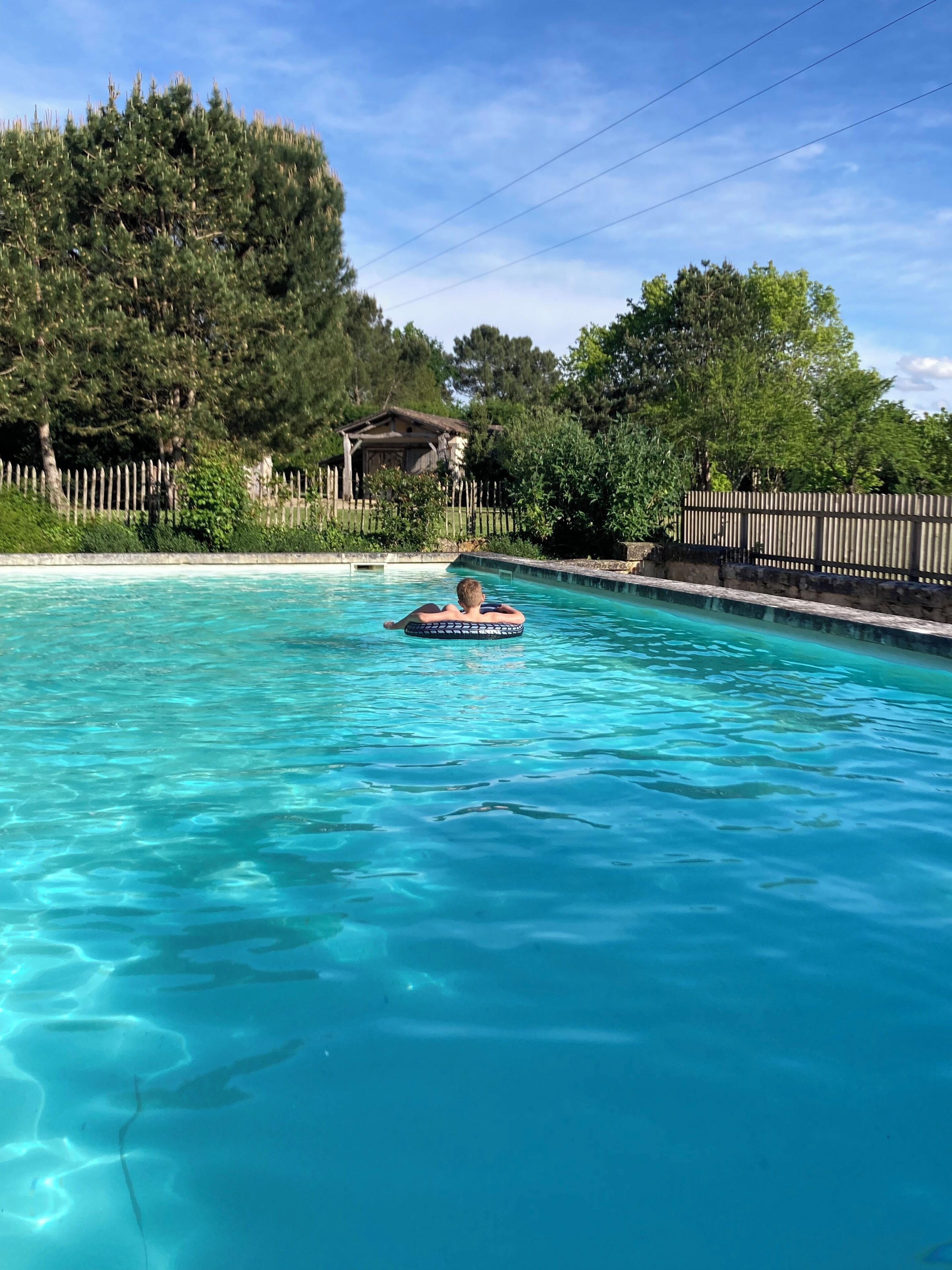 Une piscine aux eaux cristallines dans laquelle une personne flotte sur un flotteur gonflable.