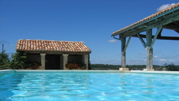A swimming pool with a tiled roof structure and a small building with a tiled roof. - Gites de Charme au Cœur du Perigord Pourpre (Saint-Remy)