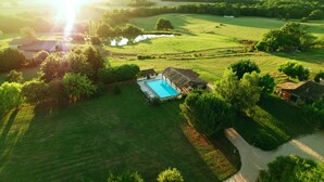 An aerial view of a property with a swimming pool, surrounded by lush green fields and trees. - Gites de Charme au Cœur du Perigord Pourpre (Saint-Remy)