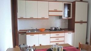 Una cucina compatta con mobili bianchi, un piano cottura a gas e un lavandino.