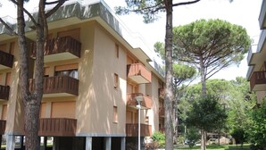 A multi-story building with balconies, surrounded by trees and a well-maintained lawn.