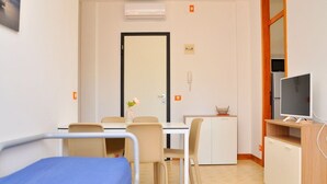 Une chambre d’hôtel comprenant un lit, un bureau avec une chaise, une télévision et un petit placard.
