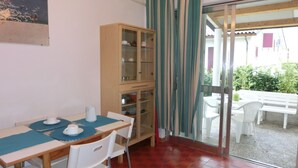 A dining area with a table, chairs, a cabinet, and a view through a glass door to an outdoor seating area. - Villa in a quiet area next to the sea (Bibione)