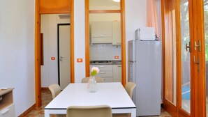 Une cuisine compacte équipée d’un réfrigérateur, d’un four à micro-ondes et d’un évier. On y trouve une table à manger avec des chaises et un vase rempli de fleurs.