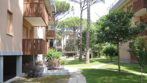 A courtyard with a pathway, trees, and a building with balconies.