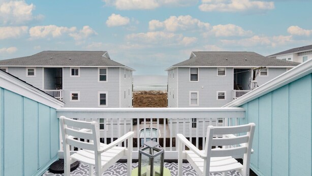 Une vue d’un immeuble doté d’un balcon et de deux chaises blanches.