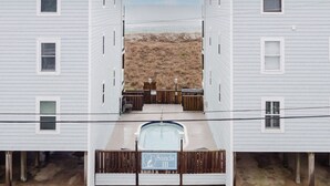 Une propriété située en bord de mer, comprenant deux maisons blanches, une piscine et une terrasse en bois.