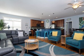 Ein modernes Wohnzimmer mit einem schwarzen Ledersofa, einem blauen Sessel und einem Holztisch.