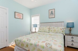 Ein Schlafzimmer mit einem Bett, einem Nachttisch, einer Lampe und zwei gerahmten Bildern an der Wand.