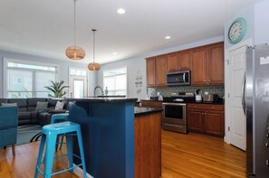 A modern kitchen with wooden cabinets, stainless steel appliances, and a blue island.