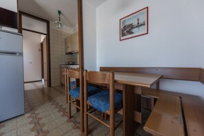 Una cocina con una mesa de comedor y sillas, un refrigerador y un cuadro colgado en la pared.