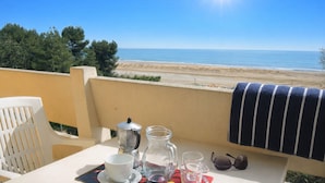 A table with a coffee maker, cups, and glasses on a balcony overlooking a beach. - Nice flat for six guests by the sea (Bibione)