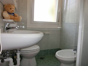 Een badkamer met toilet, hygiëneschuimer en wastafel.