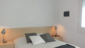 A bedroom with a bed, two bedside tables, and a window. - Comfortable apartment with parking in Bibione (Bibione)