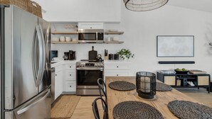 A modern kitchen with white cabinetry, stainless steel appliances, and a wooden dining table with woven placemats.