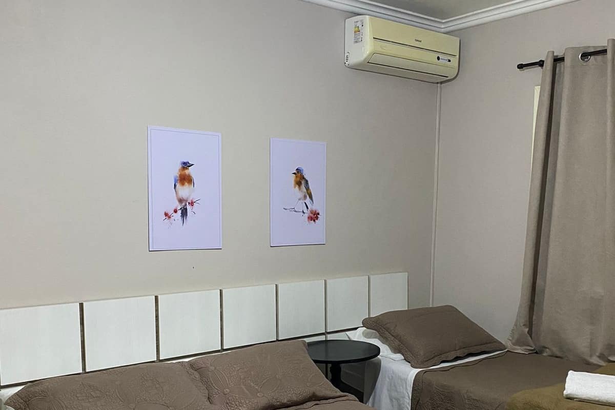 Ein Hotelzimmer mit zwei Betten, einem Nachttisch, einem kleinen runden Tisch und einer Klimaanlage an der Wand.