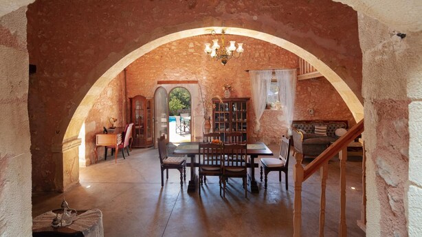 Zona pranzo con arco in pietra, arredi in legno e lampadario.