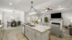 Una cocina moderna con una isla grande, armarios blancos y un comedor con mesa y sillas.
