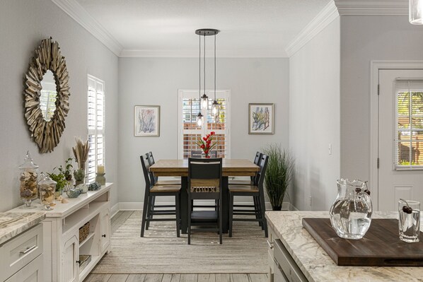 A dining area with a wooden table and chairs, a chandelier, and artwork on the walls.