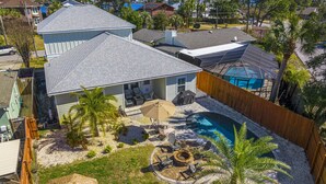 Una propiedad residencial con piscina, mobiliario de patio y jardín trasero cercado.