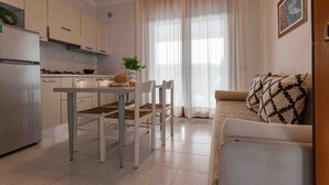 Una cocina moderna con armarios blancos, una mesa de comedor con sillas y un sofá en la zona de estar.