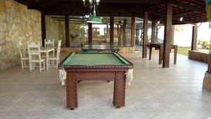 Una mesa de billar en un espacio techado con paredes de piedra y suelo de baldosas.