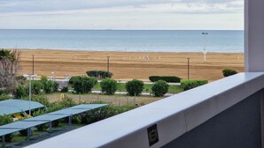 A beach view from a balcony with a clear sky, a sandy beach, and a lifeguard tower in the distance. - Comfortable apartment with a shared pool-Beahost (Bibione)
