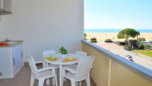 A balcony with a table and chairs, a small sink, and a view of the beach and road. - Comfortable apartment overlooking the sea (Bibione)
