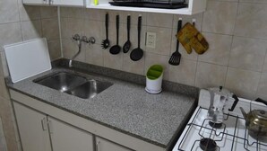 Een keuken met twee spoelbakken, een fornuis en diverse keukengerei dat aan de muur hangt.