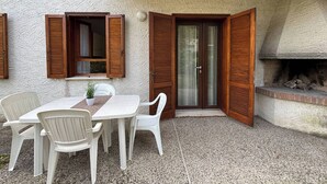 A patio with a table and chairs, a wooden door, and a fireplace. - Villa with garden 250 meters from the beach (Bibione)