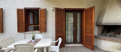 A patio with a table and chairs, a wooden door, and a fireplace.