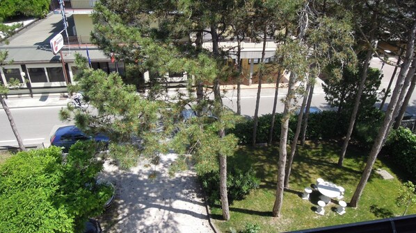 A residential area with a street, trees, and a building with a sign.