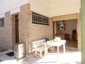 A patio area with a white table, bench, and a small refrigerator. - Beautiful flat 250m from the beach for 8 guests (Bibione)