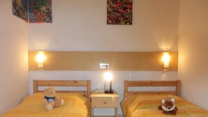 Une chambre avec deux lits, une table de chevet avec une lampe et un luminaire fixé au mur.