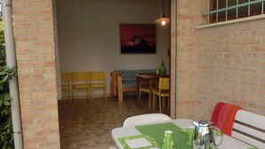 Un coin repas avec une table dressée pour deux personnes, un chemin de table vert et une cafetière en argent.