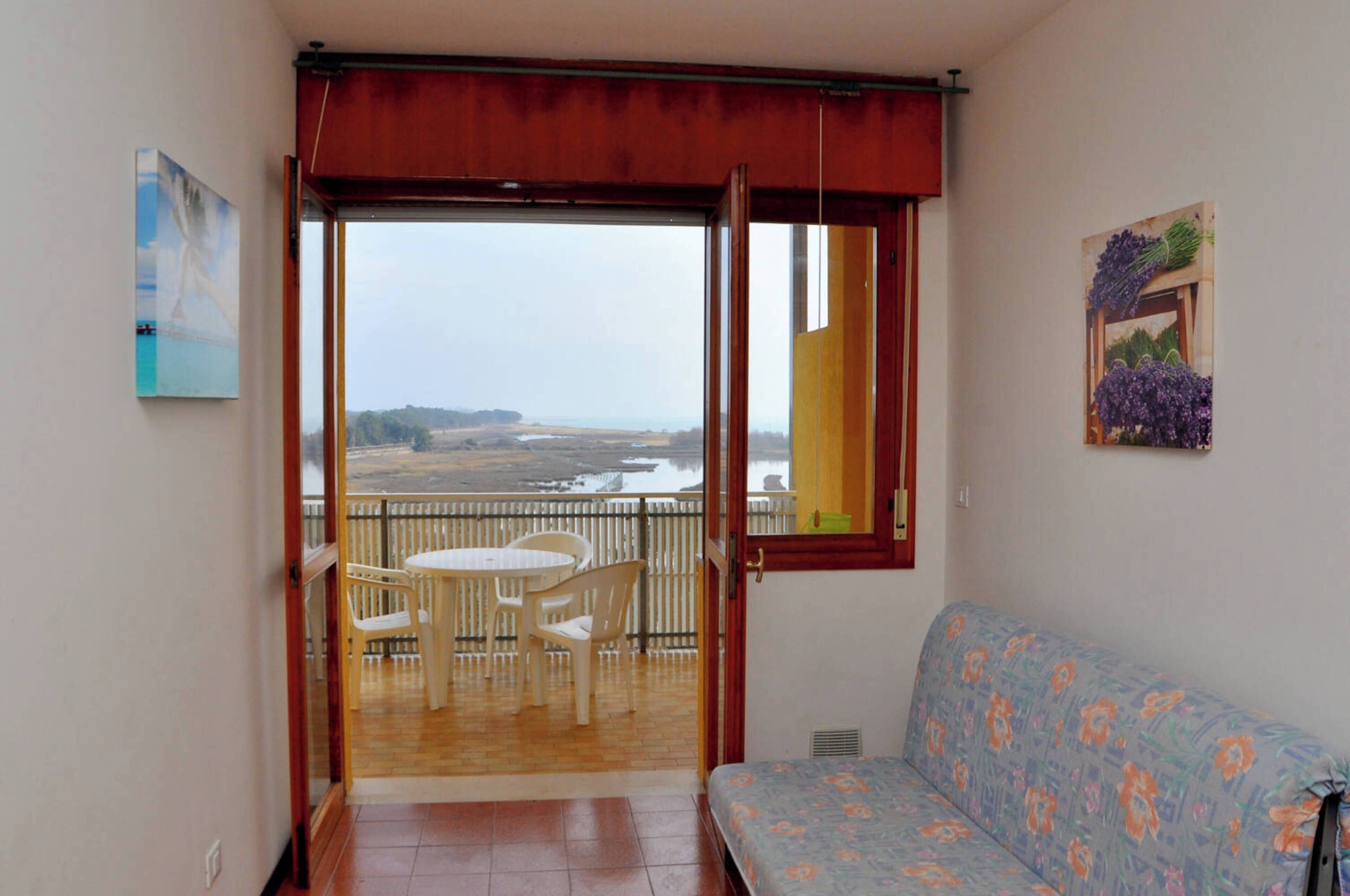 A balcony with a table and chairs, a sofa, and a view of the countryside.