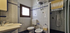 Et badeværelse med vask, toilet, bidet og brusebad.