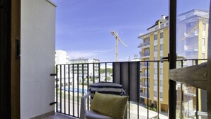Un balcon avec vue sur une grue de chantier, une piscine et les bâtiments environnants.