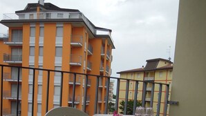 Ein Balkon mit Tisch und Stühlen, mit Blick auf ein orangefarbenes Gebäude mit Balkonen.