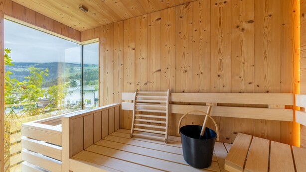 A wooden sauna with benches, a wooden ladder, and a black bucket. - wohngenuss apprtements (Schladming)