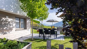 A patio area with outdoor seating, a wooden fence, and a view of mountains in the background. - wohngenuss apprtements (Schladming)