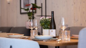 A dining table set with plates, glasses, a wine bottle, and a potted plant. - wohngenuss apprtements (Schladming)