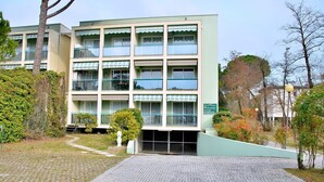 Un edificio de varios pisos con fachada verde claro, múltiples balcones y un acceso pavimentado.