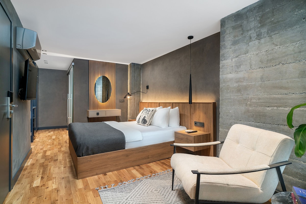 A modern bedroom with a wooden bed, a bedside table, a chair, and a large mirror on the wall.
