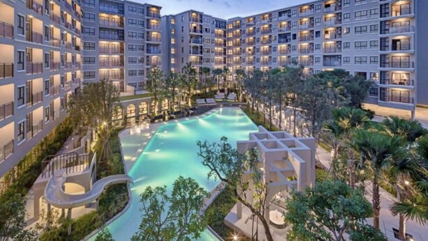 A multi-story hotel with a central swimming pool surrounded by greenery and palm trees. - La casita Hua Hin (Hua Hin)