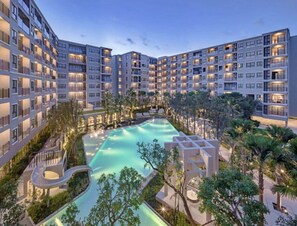A multi-story hotel with a central swimming pool surrounded by greenery and palm trees. - La casita Hua Hin (Hua Hin)