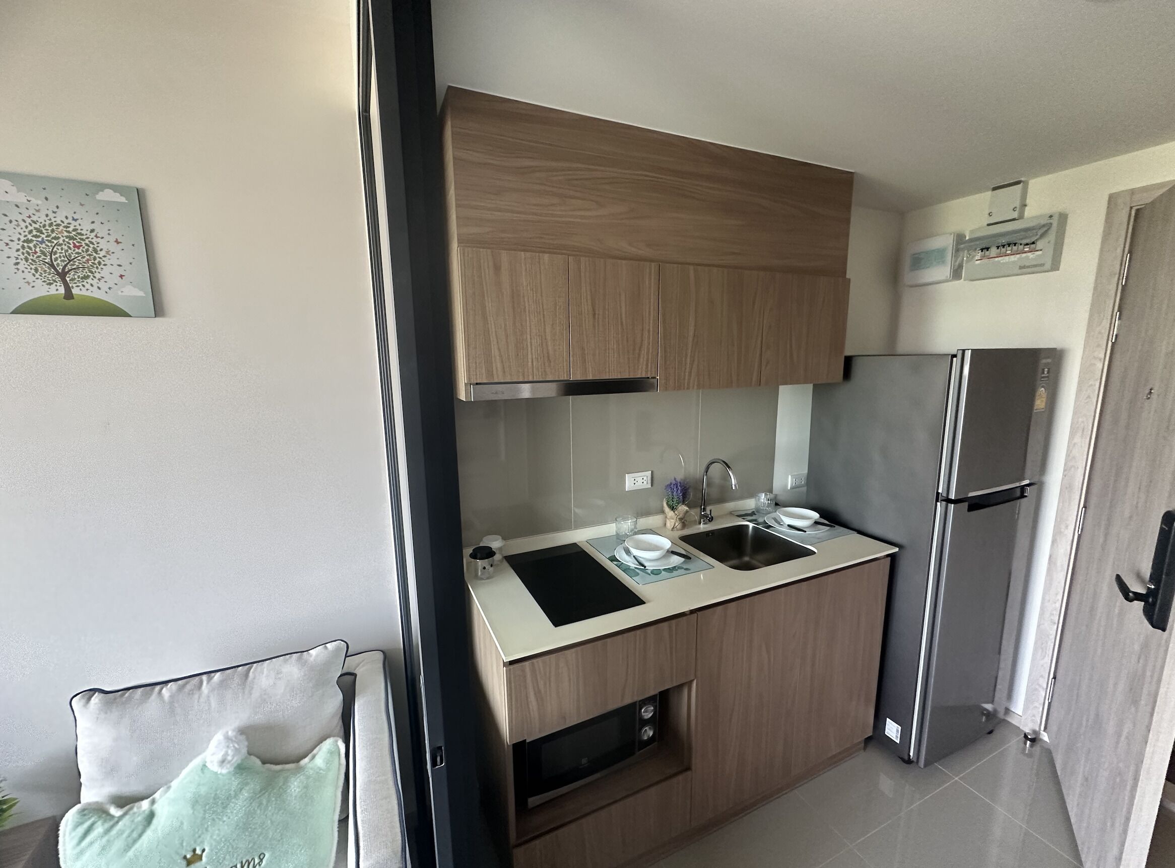Una cucina compatta con mobili in legno, un frigorifero in acciaio inossidabile e un lavello.