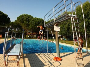 A swimming pool with diving platforms and ladders, surrounded by trees. - Family flat in a residence with 3 pools-Beahost (Bibione)