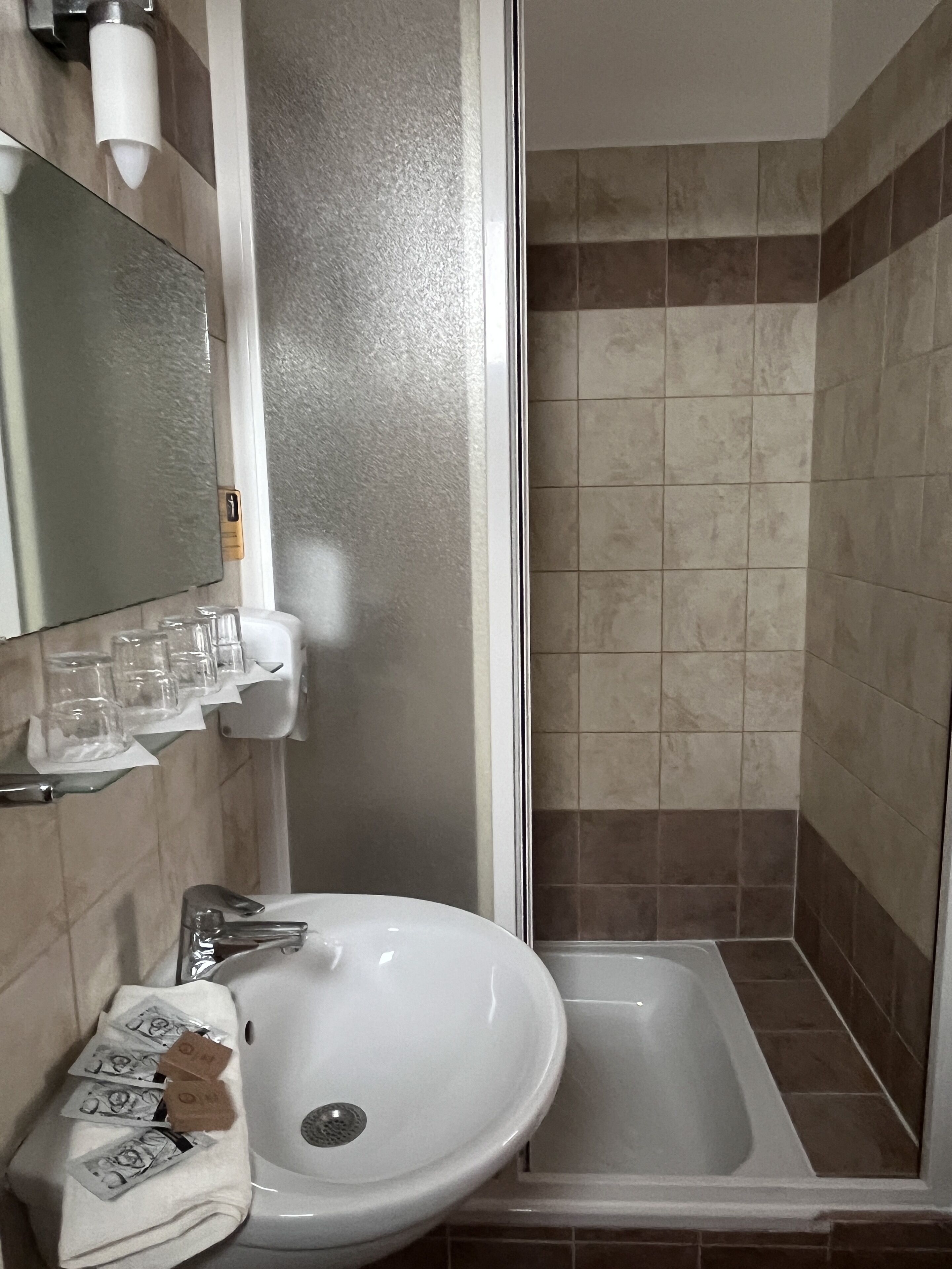 Casa de banho com lavatório branco, espelho e zona de duche.