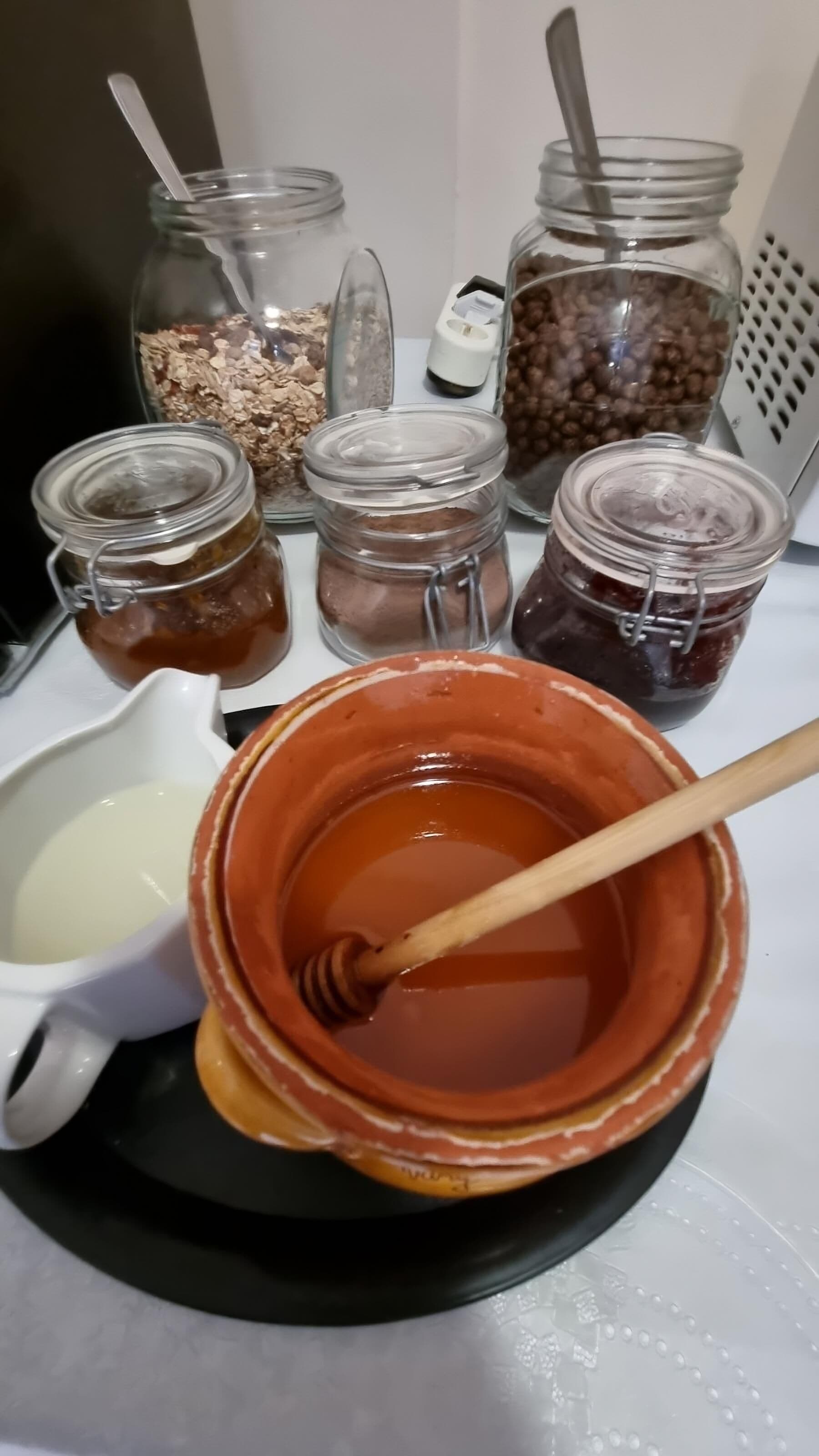 A table with jars of honey, a honey dipper, and a bowl of honey.